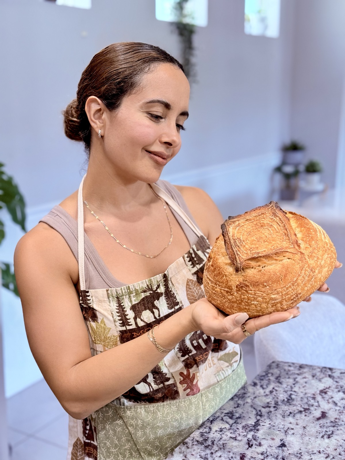 Stephanie Azcona looking down at her sourdough loaf with quiet pride